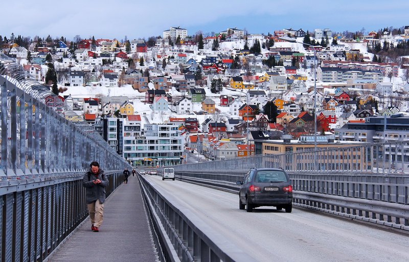 En mann og en bil beveger seg over Tromsø brua.