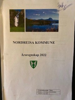 Fremsiden av Nordreisa kommunes årsregnskap for 2022 - i papirformat. Rådmann Jørn Hugo har underskrevet årsregnskapet.