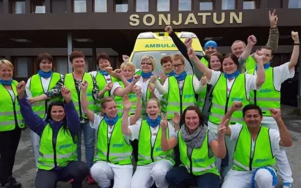 Gruppebilde av ansatte i Nordreisa kommune if&oslash;rt gr&oslash;nne refleksvester, st&aring;ende samlet utenfor inngangen til Sonjatun helsesenter