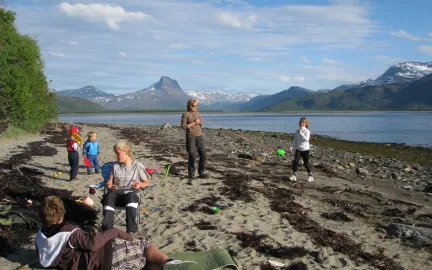 Barn og voksne i fj&aelig;ra med fjord og fjell i bakgrunnen.