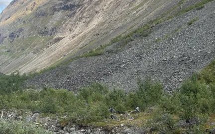 Steinras har etterlatt et lyst rasomr&aring;de i fjellsiden i Moskodalen. Elva renner i forgrunnen.