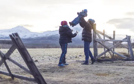 To voksne leker med et lite barn ute i et vinterlandskap.