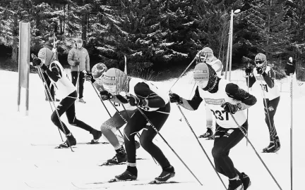 Flere skil&oslash;pere g&aring;r p&aring; ski sammen i et preparert skispor - sort/hvitt