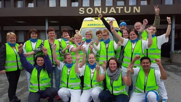 Gruppebilde av ansatte i Nordreisa kommune if&oslash;rt gr&oslash;nne refleksvester, st&aring;ende samlet utenfor inngangen til Sonjatun helsesenter