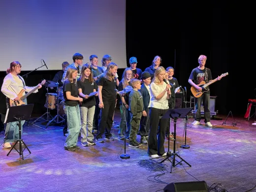 Kulturskolen på scenen Mange barn står på en scene, noen synger og noen spiller instrumenter
